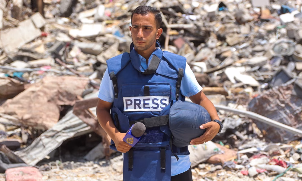 An image of Journalist Anas al-Sharif standing in front of Rubble in Gaza