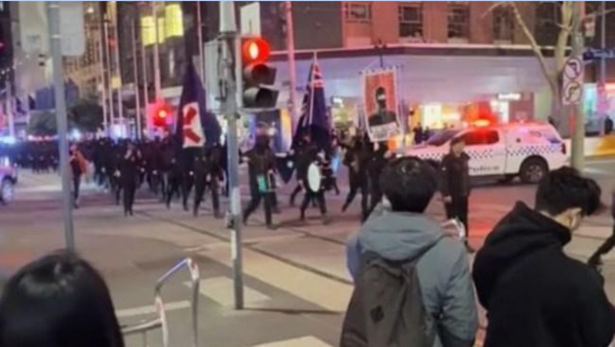 An image of 100 Neo-Nazis marching in the middle of the Melbourne CBD, onlookers watching.